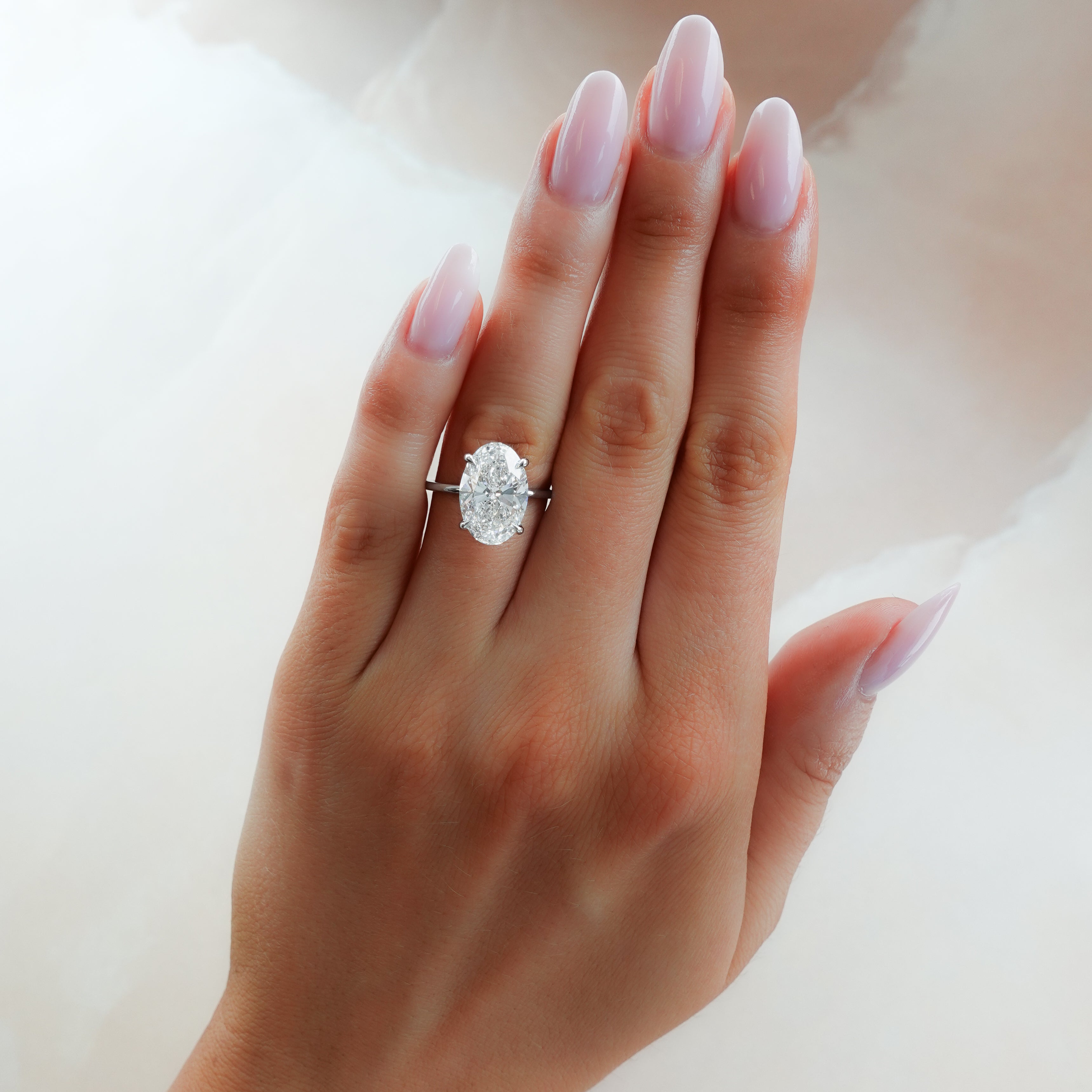 Hand wearing an oval diamond solitaire ring, editorial lifestyle photography