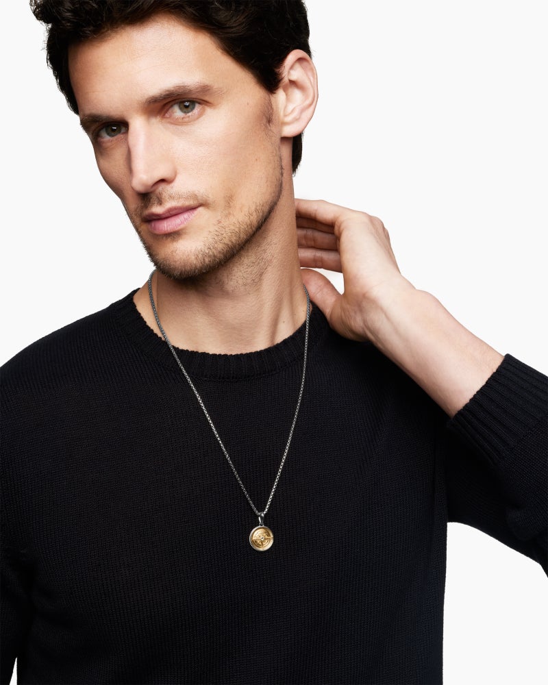 David Yurman Maritime Compass Amulet in sterling silver with 18k yellow gold, worn by a man in a black crewneck sweater